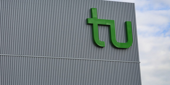 Das große Logo der TU an einem Gebäude.