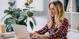 Frau sitzt vor einem Laptop und tippt